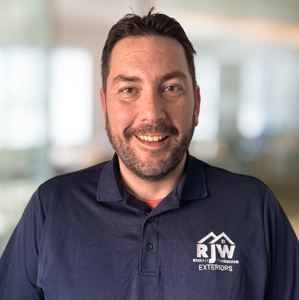 RJW Exteriors employee in blue polo, indoors, smiling.